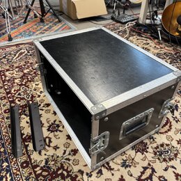 Černý transportní flightcase s hliníkovými hranami a rohy. Na přední straně je umístěna jedna černá plastová rukojeť a dva kovové zámky. Vedle kufru…