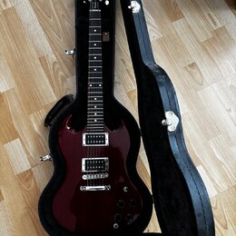 Tmavě červená elektrická kytara s tmavým hmatníkem v černém tvrdém kufru. Na hlavě nástroje je viditelné logo Gibson. Tělo kytary má dva humbuckery,…