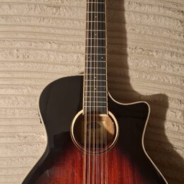 Akustická kytara s cutawayem a tmavě červeným přechodem do černé barvy (sunburst). Na hlavě hmatníku je viditelné logo "Cort". Nástroj vykazuje čistý…