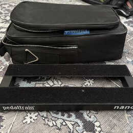 Černý kovový pedalboard s dvěma vodorovnými nosnými lištami. Na spodní hraně je bílý nápis pedaltrain® U.S. Pat. No. 7,439,023 a označení nano. Vedle…