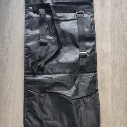 Černý obdélníkový obal z syntetického materiálu s jemným leskem. V horní části jsou dvě černé popruhy s plastovými přezkami a šitými úchyty. Povrch m…