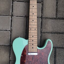 Světle zelená elektrická kytara typu Telecaster s javorovým hmatníkem a tmavě červeným šasi z vymyšleného perleťového plastu. Na hlavě je viditelné k…