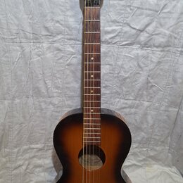 Akustická kytara s tmavě hnědým přechodem do žluté barvy (sunburst). Na hlavě je bílý nápis Framus. Nástroj vykazuje známky opotřebení, zejména v pod…