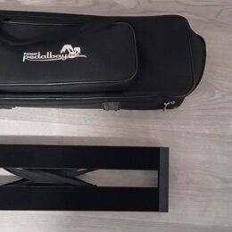Na fotografii je černý obdélníkový stojan na nástroj a černý polstrovaný pouzdro. Na pouzdře je bílý nápis „Pedalbaby“ a nad ním menší text „Patent“.…