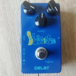 Modrý efekt pedál s nápisem DELAY v dolní části. Na horní straně jsou tři černé ovládací knoflíky s popisky LEVEL, REPEAT a DELAY. Uprostřed je nápis…