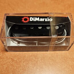 Černý humbucker v průhledném plastovém obalu. Na horní části obalu je červenobílý nápis DiMarzio s logem ozubeného kola. Na spodní hraně obalu jsou v…