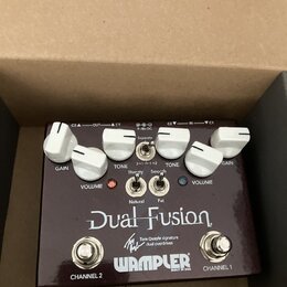 Tmavě hnědý kytarový pedál s bílými popisky a ovládacími knoflíky. Na povrchu je uveden název Dual Fusion, nápis Tom Quayle signature dual overdrives…