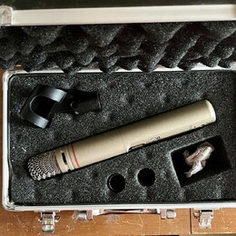 V hliníkovém kufru s černou pěnovou výplní je umístěn kondenzátorový mikrofon v béžové barvě s kovovou síťkou. Na těle mikrofonu je viditelný nápis "…
