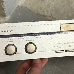 Stříbrný stereo zesilovač značky HITACHI, model STEREO AMPLIFIER HA-3700. Na předním panelu jsou umístěny čtyři otočné ovladače, několik tlačítek a p…
