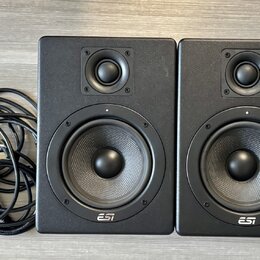 Dva černé studiové monitory s logem ESI v dolní části. Každý reproduktor obsahuje jeden výšký a jeden středně-nízký měnič. Vedle monitorů je srolovan…