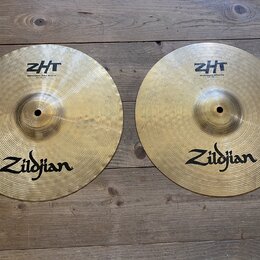 Dvě mosazné činely značky Zildjian s viditelným rakováním. Levý činel nese nápisy ZHT a Mastersound Hihat Bottom 13"/33 cm. Pravý činel má nápisy ZHT…