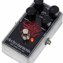 Šedý efekt pedál s povrchem z plstěného materiálu a černým ovládacím panelem. Na panelu je červený nápis Bass Soul Food a bílý nápis electro-harmonix…
