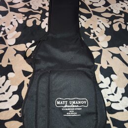 Černý polstrovaný obal na kytaru s přední kapsou. Na spodní části je bílý nápis MATT UMANOV Guitars, pod ním text 273 BLEECKER STREET N.Y.C. (212) 67…
