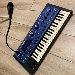Modrý klávesový syntetizátor s bílými a černými klávesami. Na horním panelu je nápis MININOVA a logo Novation. Přístroj obsahuje několik otočných kno…