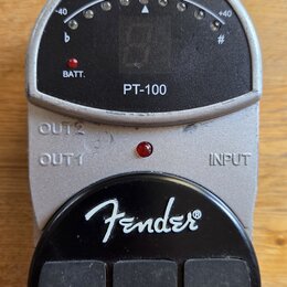 Stříbrný ladicí pedál s černým displejem a ovládacími prvky. Na přístroji jsou nápisy PT-100, BATT., OUT 2, OUT 1 a INPUT, v dolní části je bílé logo…