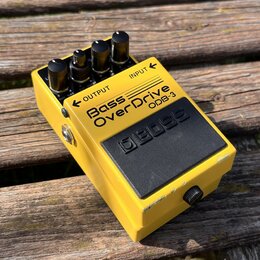 Žlutý efekt pedál s černou gumovou podložkou a čtyřmi ovládacími knoflíky. Na horní části je nápis Bass OverDrive ODB-3 a označení vstupů INPUT a OUT…