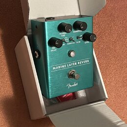 Tyrkysový efekt pedál s kovovým povrchem v kartonové krabici. Na přední straně je nápis MARINE LAYER REVERB a logo Fender. Pedál má čtyři ovládací kn…