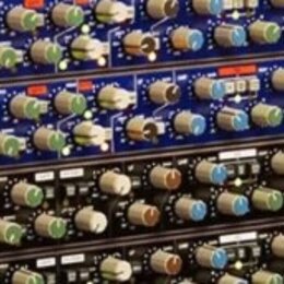 Fotografie ukazuje čtyři rackové jednotky audio procesorů naskládané nad sebou. Horní dvě jednotky mají modré přední panely, spodní dvě jsou černé. V…