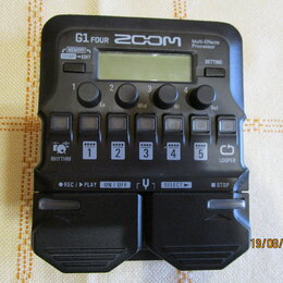 Černý multi-efektový procesor s nápisy G1 FOUR, ZOOM a Multi-Effects Processor. Zařízení má malý displej, čtyři otočné ovladače s popisky Lo, Mid, Hi…