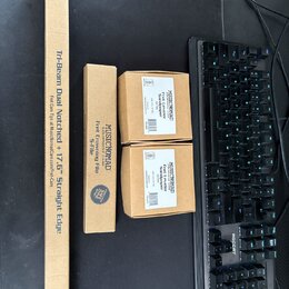 Na fotografii jsou čtyři kartonové krabice s nářadím značky MUSICNOMAD. Největší úzká krabice nese nápis „Tri-Beam Dual Notched + 17.6" Straight Edge…