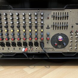 Šedý mixážní pult v černém transportním kufru. Na pravé straně je svisle napsáno logo Soundcraft a v dolní části nápisy GIGRAC 1000sc, GIG a combined…