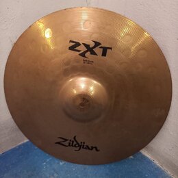 Kruhová mosazná činely s viditelným žebrováním. Na povrchu jsou nápisy ZXT, Rock Crash a 18"/45cm, v dolní části je logo Zildjian. Povrch vykazuje dr…