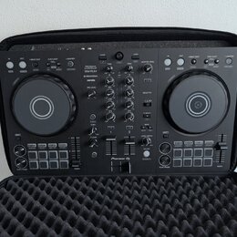 Černý DJ kontrolér Pioneer DJ model DDJ-FLX4 umístěný v černé polstrované přepravní brašně. Na přístroji jsou viditelné nápisy rekordbox a serato. Po…