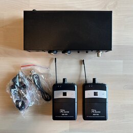Černý bezdrátový systém pro in-ear monitoring. Sada obsahuje jeden hlavní vysílač a dva malé přijímače s anténami, z nichž oba mají bílý nápis „the e…
