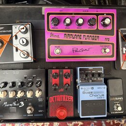 Sestava efektových pedálů na černém pedalboardu. V horní řadě jsou pedály Behringer BASS BRASSMASTER FUZZ, Ibanez AIRPLANE FLANGER AF2 a Electro-Harm…