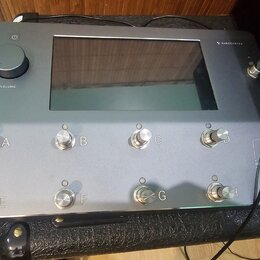 Šedý kytarový procesor s velkým displejem uprostřed. V pravém horním rohu je nápis QUAD CORTEX a vlevo knoflík s popiskem VOLUME. Přístroj má osm stř…