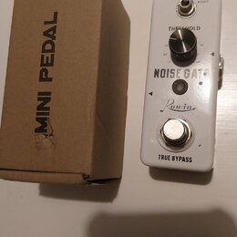 Bílý efekt pedál s nápisy NOISE GATE, Rowin a TRUE BYPASS. Obsahuje jeden ovládací knoflík s popiskem THRESHOLD a přepínač s označením HARD / SOFT. V…