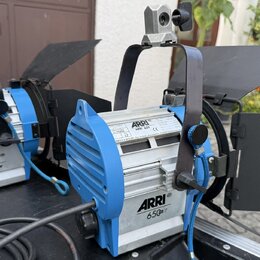 Dvě stříbrno-modré studiové lampy s černými klapkami. Na obou je vidět nápis ARRI 650. Pravá lampa má štítek s textem ARRI, ARRI 650 a číslem 32 7940…