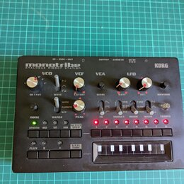 Černý kompaktní syntetizátor s nápisy monotribe ANALOGUE RIBBON STATION a KORG. Přístroj obsahuje několik otočných potenciometrů, přepínačů a řadu tl…