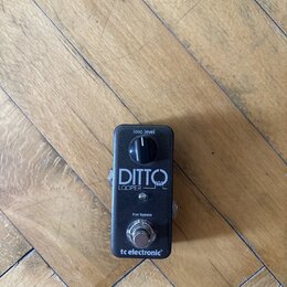 Černý kytarový pedál s nápisy „loop level“, „DITTO LOOPER“ a „true bypass“. Ve spodní části je umístěno logo „tc electronic“. Zařízení má jeden ovlád…