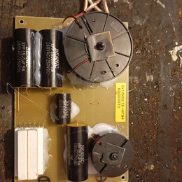 Fotografie znázorňuje elektronickou desku s osazenými komponenty. Na desce jsou čtyři černé válcové kondenzátory s bílým nápisem BENNIC, dva z nich m…