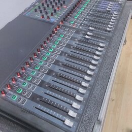 Šedočerný mixovací pult s posuvníky a řadou ovládacích knoflíků. V levém horním rohu je bílý nápis Soundcraft a vedle něj označení modelu SX. Zařízen…