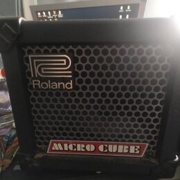 Černý kytarový kombo zesilovač s kovovou mřížkou reproduktoru. Na přední straně je umístěno logo Roland a nápis MICRO CUBE v červeném rámečku. Povrch…