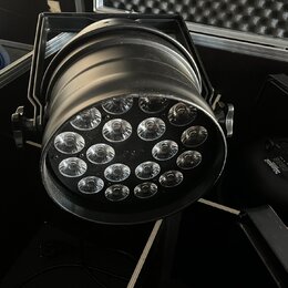 Černý LED reflektor v kovovém provedení s 12 svítícími elementy. Zařízení je umístěno v transportním kufru s pěnovou výplní. Na těle reflektoru nejso…