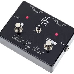Černý efekt pedál s nápisem Dual Loop Switch. Na horní straně je logo HB, přepínač s označením A/B a A+B, dva stoupací spínače s popisky B a A/(A+B)…