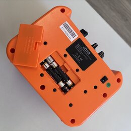 Zadní strana oranžového efekt pedálu značky JOYO. Na černé štítku je nápis „JOYO MINI PEDAL FOR ELECTRIC GUITAR MODEL: JA-01 POWER SUPPLY: 9V DC - (c…