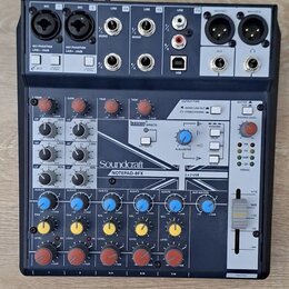 Mixážní pult s modrým povrchem a černým rámem. Na předním panelu je bílý nápis Soundcraft a pod ním model NOTEPAD-8FX. V horní části je sekce EFFECTS…