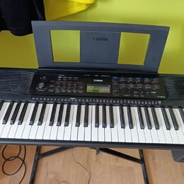 Černý digitální klavír s bílými a černými klávesami, umístěný na černém stojanu. Na horním panelu a na notovém pultu je bílé logo YAMAHA. V pravé čás…