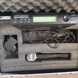 V hliníkovém kufru s pěnovou výplní je umístěn bezdrátový mikrofonní systém. Černý přijímač nese nápisy AWM200 WIRELESS MICROPHONE SYSTEM, UHF a logo…