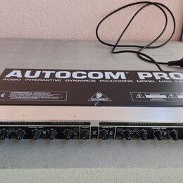 Stříbro-černý rackový procesor s nápisem AUTOCOM PRO AUDIO INTERACTIVE DYNAMICS PROCESSOR MODEL MDX 1400. Na horním panelu je logo BEHRINGER, značka…