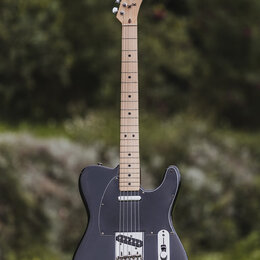 Elektrická kytara typu Telecaster v černé barvě s černým pickguardem a světlým hnedým hmatníkem. Na hlavě je viditelné logo Fender Telecaster. Tělo v…