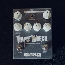 Stříbrný efekt pedál s nápisy TRIPLE WRECK a Modern Rectified Distortion. V dolní části je logo WAMPLER s doplňkem BUILT IN USA. Pedál má šest bílých…