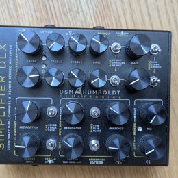 Černý kytarový procesor s nápisem SIMPLIFIER DLX a logem DSM HUMBOLDT ELECTRONICS. Zařízení obsahuje několik otočných potenciometrů s popisky jako LE…