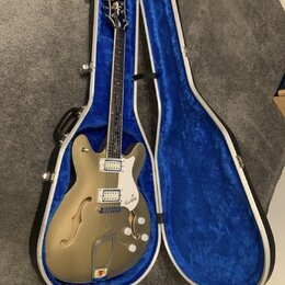 Polodupatá elektrická kytara v zlatavé barvě s bílým pickguardem a dvěma snímači. Na hlavě hmatníku je nápis „Epiphone“ a na pickguardu je logo „Epip…