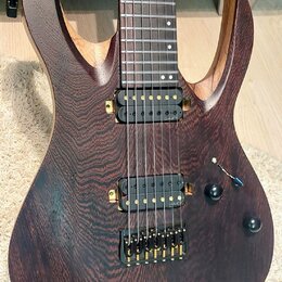 Elektrická kytara s tmavě hnědým dřevěným povrchem a výraznou strukturou zrna. Nástroj má dva humbuckery s černými snímači a zlatým hardwarem, včetně…