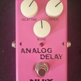Růžový efekt pedál Analog Delay s třemi bílými oválnými knoflíky označenými jako DELAY TIME, REPEAT a BLEND. Na spodní části je nápis ANALOG DELAY, l…